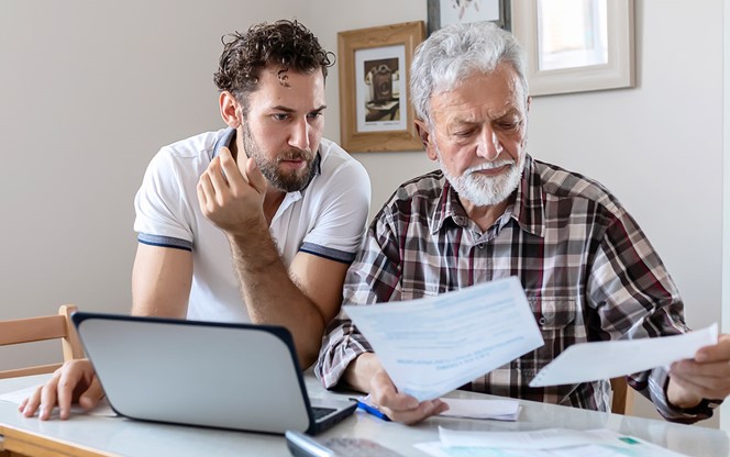 Adult Son With His Troubled Father Discussing Finance Budget Paperwork