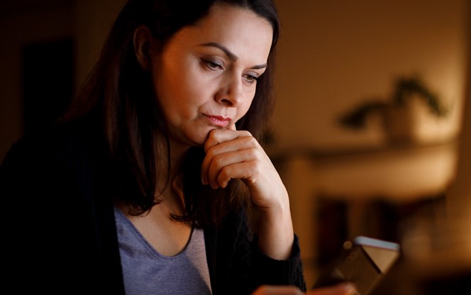 Worried Mature Woman Working Late At Home Looking At Her Phone