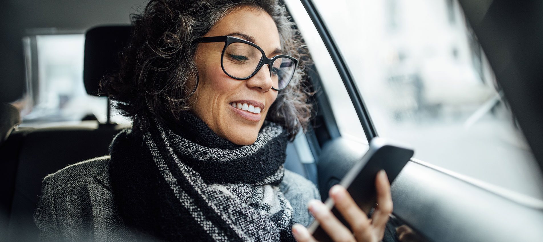 Mature Businesswoman Using Phone While Traveling By A Taxi