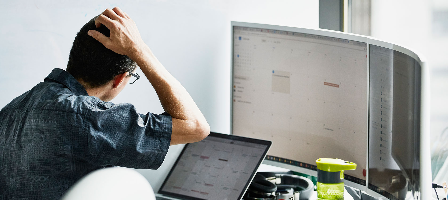 Man Scratching Head While Looking At Calendar On Computer Monitor