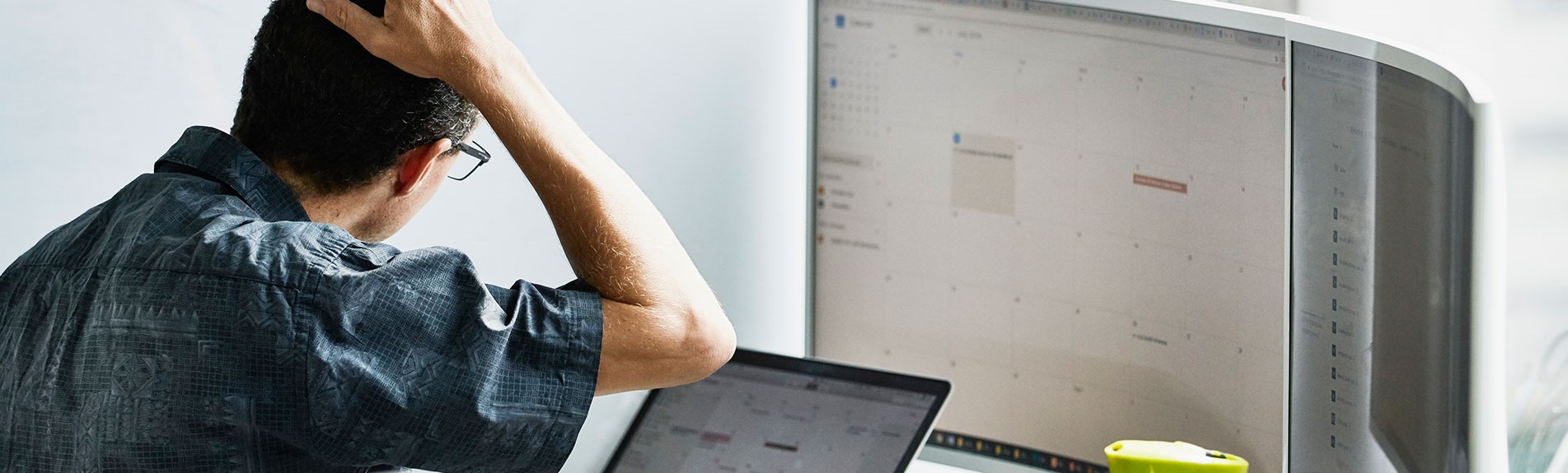 Man Scratching Head While Looking At Calendar On Computer Monitor