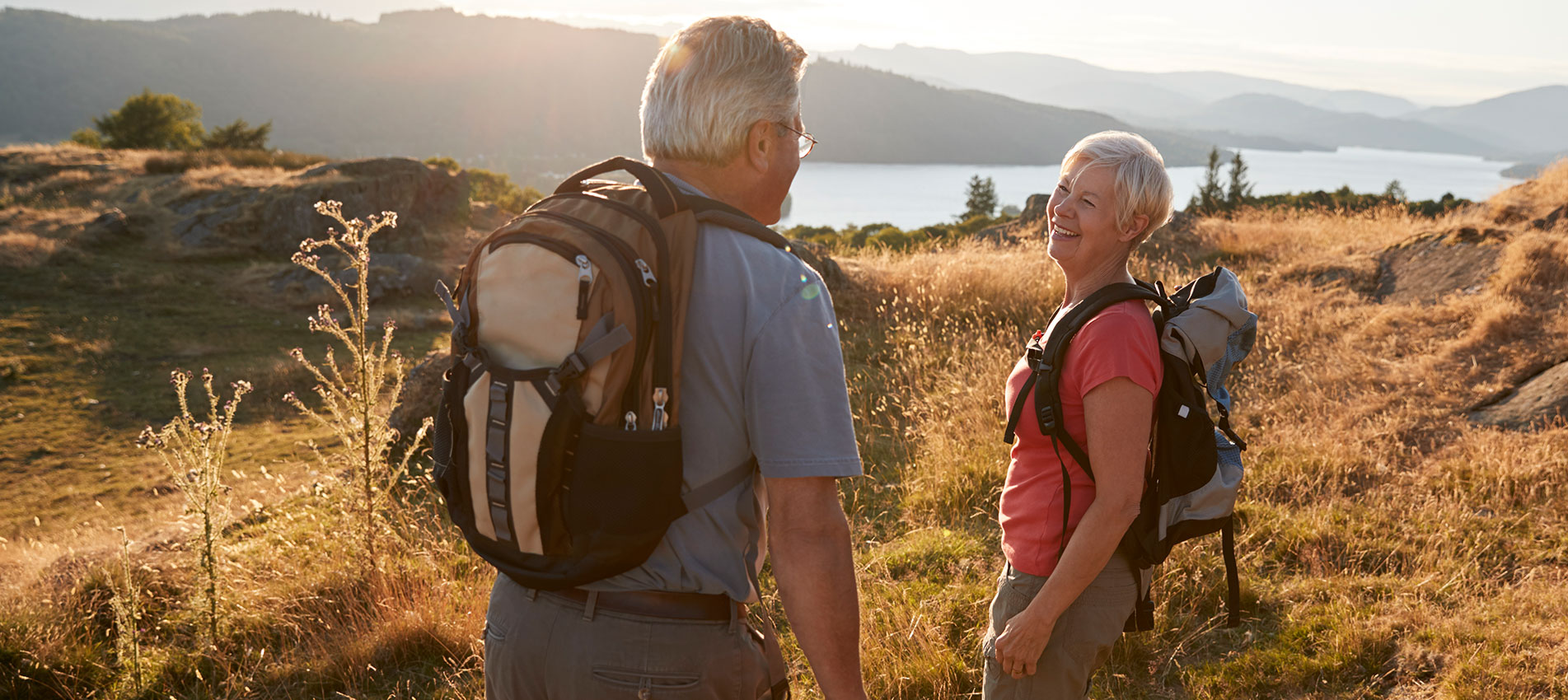 Senior Couple Walking On Top Of Hill On Hike Through Countryside