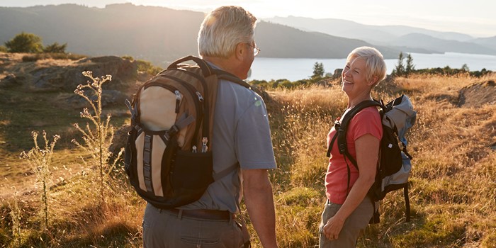 Senior Couple Walking On Top Of Hill On Hike Through Countryside