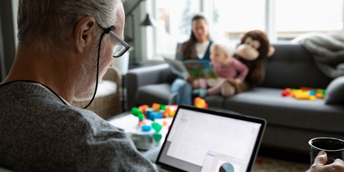 Senior Man Using Laptop And Drinking Coffee In Living Room