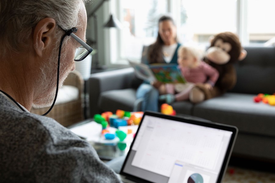 Senior Man Using Laptop And Drinking Coffee In Living Room