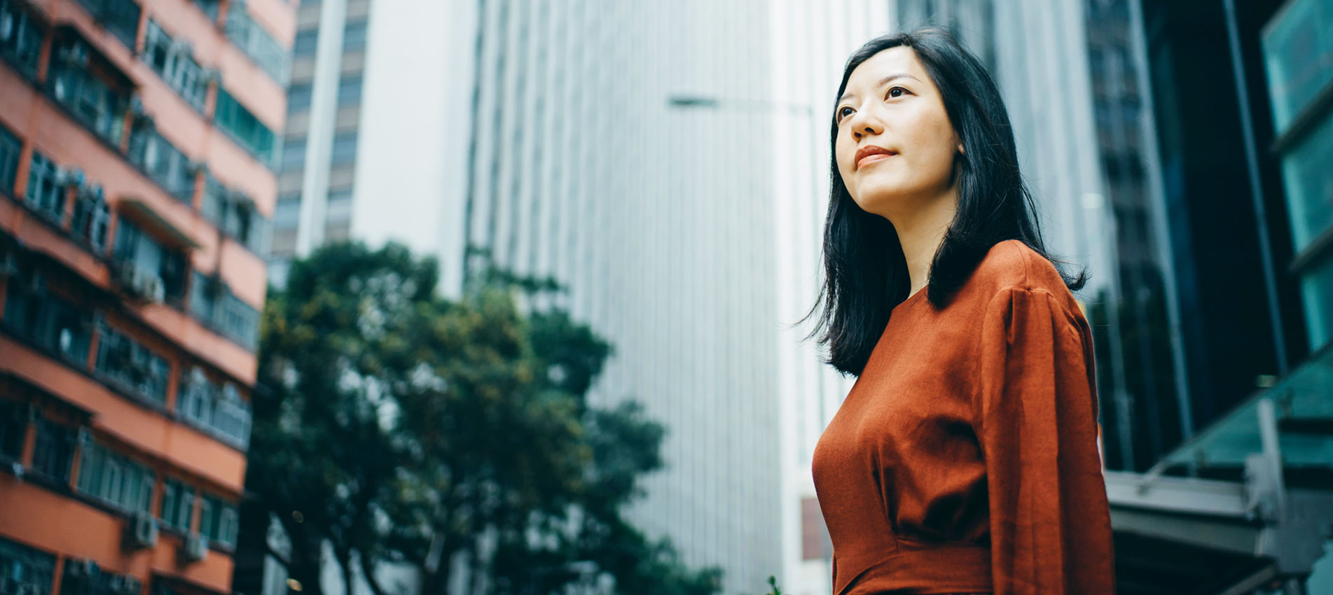 Portrait Of Confidence Young Woman Standing Against Highrise City Buildings In City
