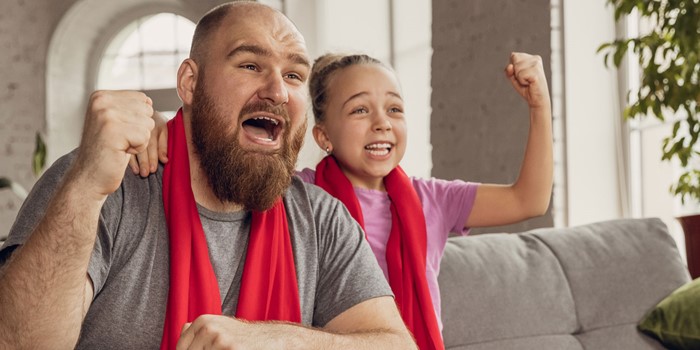 Excited, Happy Daughter And Father Watch Sports Together On The Couch