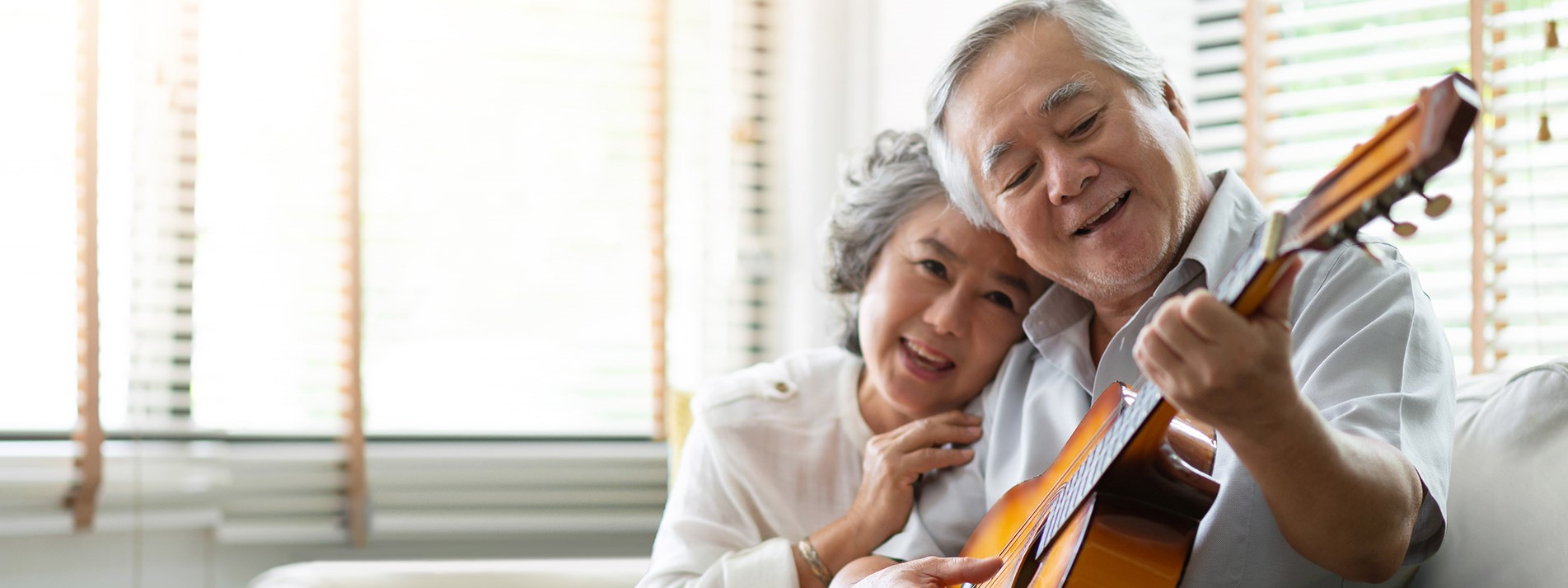Happy Asian Senior Couple Enjoying With Singing And Playing Guitar Together