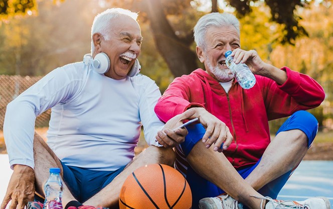 Two Active Senior Men On Basketball Field Taking A Break From Sport Activity