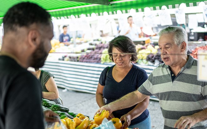 Senior Couple Customer Choosing Fruits And Vegetables On A Street Market