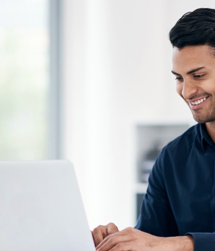 Young Businessman Using A Laptop At His Desk In A Modern Office