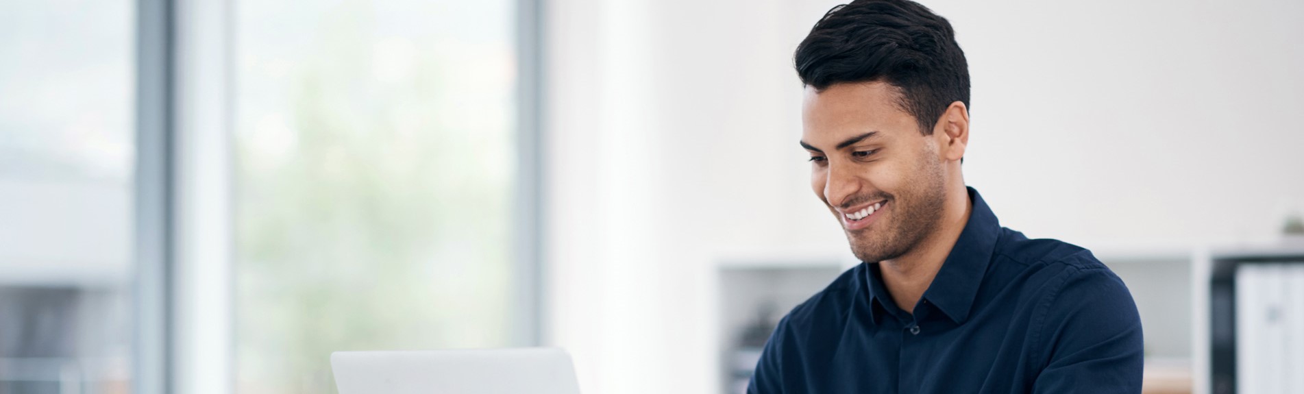 Young Businessman Using A Laptop At His Desk In A Modern Office